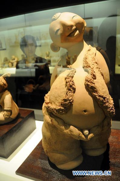 A visitor looks at a piece of mud sculpture at Hebei Folklore Museum in Shijiazhuang, capital of north China's Hebei Province, Sept. 26, 2010. The folklore museum started recently an exhibition of mud sculptures featuring country lives.