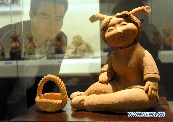 A visitor looks at a piece of mud sculpture at Hebei Folklore Museum in Shijiazhuang, capital of north China's Hebei Province, Sept. 26, 2010. The folklore museum started recently an exhibition of mud sculptures featuring country lives.