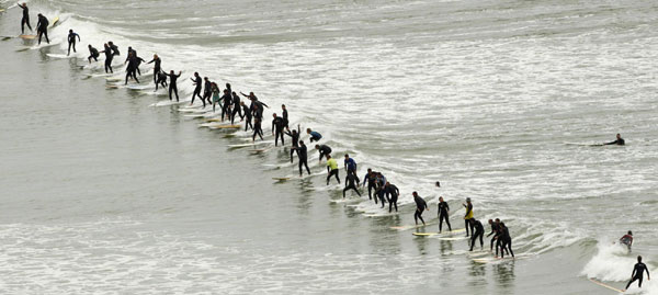 South African surfers take to the water in an attempt to break the Guinness World Record for the highest number of riders on a single wave at Muizenberg in Cape Town, Sept 26, 2010. [China Daily/Agencies]