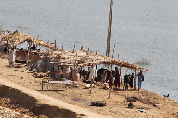 People wait for relief materials to be airdropped by two Chinese People&apos;s Liberation Army helicopters in flood-hit Pakistan, Sept 27, 2010. [Xinhua]