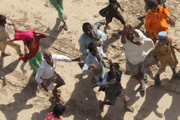 People run for relief materials dropped by a Chinese People&apos;s Liberation Army helicopter in flood-hit Pakistan, Sept 27, 2010. [Xinhua]