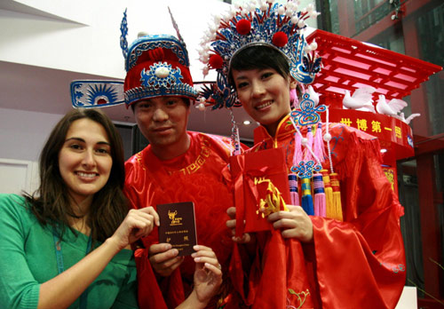 A foreign tourist takes pictures with a couple during a traditional folk wedding ceremony at the Shanghai World Expo, Sept 27, 2010. Expo witnessed its first Southern Chinese folk wedding ceremony as 20 couples from East China&apos;s Jiangsu and Zhejiang provinces and Shanghai municipality held a group wedding at the site, sharing their love and happiness with other Expo visitors. [Xinhua]