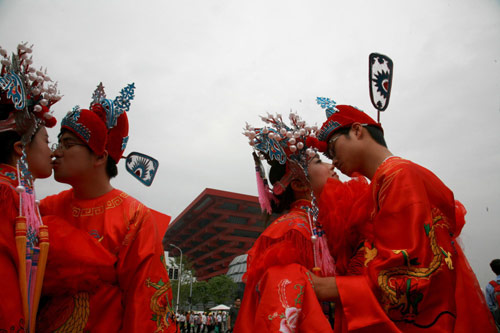 Newly married couples kiss during a traditional folk wedding ceremony in front of the China Pavilion at the Shanghai World Expo, Sept 27, 2010. [Xinhua]