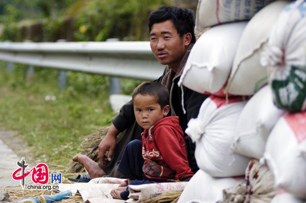 A man and his son sit by the roadside at a village near the Xichang Satellite Launch Center, Southwest China&apos;s Sichuan province, on Tuesday, Sept 28, 2010. China&apos;s second lunar probe, the Chang&apos;e-2, is set to blast off from Xichang, on or around National Day. As a safety precaution, more than 2,000 residents within 2.5 kilometers of the launch pad will be evacuated hours before lift-off, media reports said. [CFP]