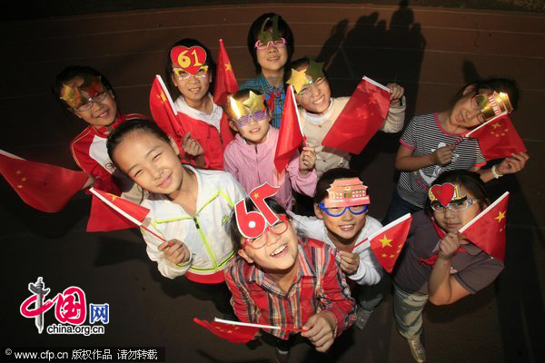 Students wearing specially-designed Tian&apos;anmen glass ornaments smile before the cameras during the &apos;I Love You, China&apos; day in Tianjin as the 61st anniversary of National Day approaches. [CFP]