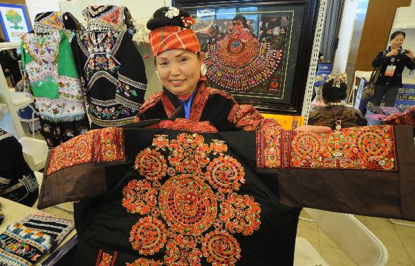 A woman of Miao ethnic group shows an embroidery during a tourism products designing contest held in Guiyang, capital of southwest China's Guizhou Province, Sept. 29, 2010. Some 300 folk artists took part in the two-day contest, presenting more than 600 art works. [Xinhua photo]