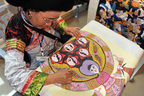 A woman makes a painting during a tourism products designing contest held in Guiyang, capital of southwest China's Guizhou Province, Sept. 29, 2010. Some 300 folk artists took part in the two-day contest, presenting more than 600 art works. [Xinhua photo]