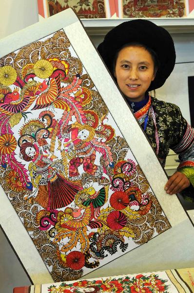 A woman of Miao ethnic group shows an encaustic art work during a tourism products designing contest held in Guiyang, capital of southwest China's Guizhou Province, Sept. 29, 2010. Some 300 folk artists took part in the two-day contest, presenting more than 600 art works. [Xinhua photo]