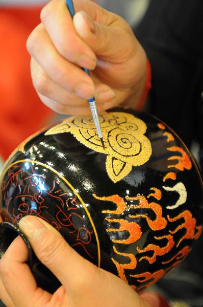 A folk artist makes lacquer paintings during a tourism products designing contest held in Guiyang, capital of southwest China's Guizhou Province, Sept. 29, 2010. Some 300 folk artists took part in the two-day contest, presenting more than 600 art works. [Xinhua photo]