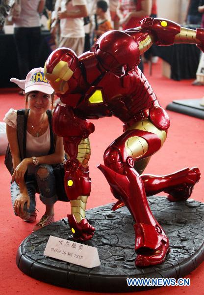 A girl poses with a model of a Hollywood movie character the Iron Man produced by a local studio at a comic and animation exhibition in Dongguan, south China&apos;s Guangdong Province, Oct. 4, 2010. [Chen Fan/Xinhua]