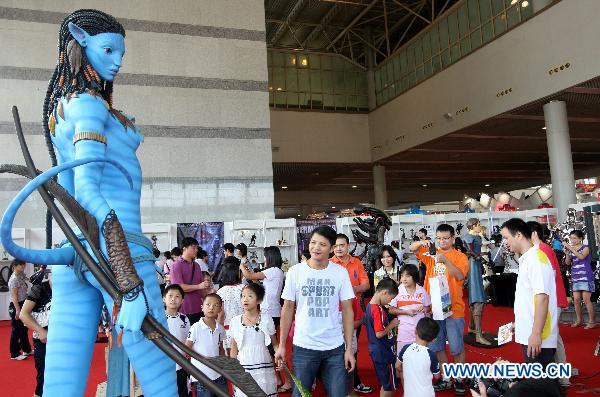 Visitors look at a model of a character of Hollywood movie &apos;Avatar&apos; produced by a local studio at a comic and animation exhibition in Dongguan, south China&apos;s Guangdong Province, Oct. 4, 2010. [Chen Fan/Xinhua]