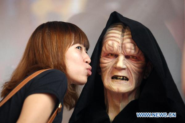 A girl poses with a model of a Hollywood movie character produced by a local studio at n comic and animation exhibition in Dongguan, south China&apos;s Guangdong Province, Oct. 4, 2010. [Chen Fan/Xinhua]