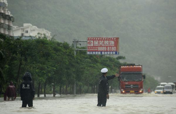 Policemen direct city traffic in rain in Sanya, south China's Hainan Province, Oct. 5, 2010. Heavy rains will hit Leizhou Peninsula and Hainan Province where heavy rain has pounded for four days and the average precipitation has exceeded 200 mm in most parts, according to the local weather bureau. [Xinhua/Xu Qintao]