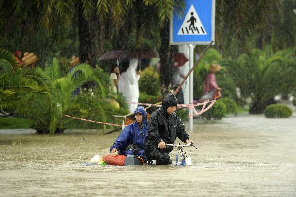 People ride in rain in Sanya, south China's Hainan Province, Oct. 5, 2010. Heavy rains will hit Leizhou Peninsula and Hainan Province where heavy rain has pounded for four days and the average precipitation has exceeded 200 mm in most parts, according to the local weather bureau. [Xinhua/Xu Qintao]