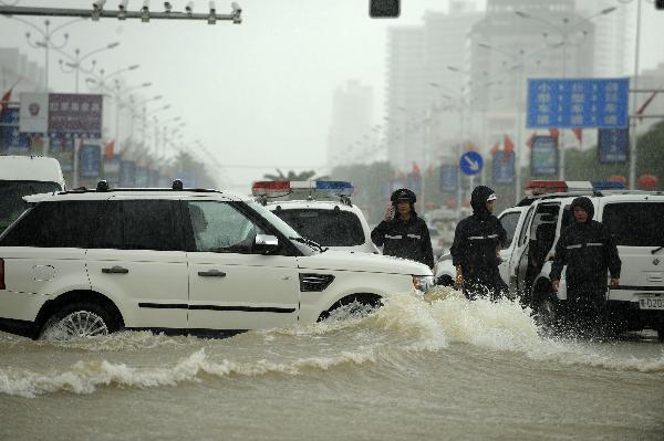 Policemen direct city traffic in rain in Sanya, south China's Hainan Province, Oct. 5, 2010. Heavy rains will hit Leizhou Peninsula and Hainan Province where heavy rain has pounded for four days and the average precipitation has exceeded 200 mm in most parts, according to the local weather bureau. [Xinhua/Xu Qintao]