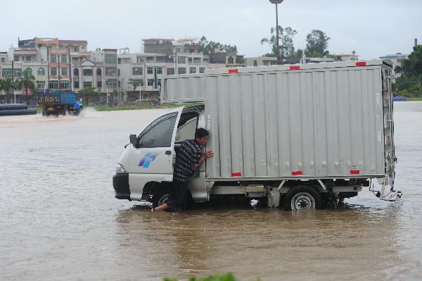 A driver tries to push his switched-off vehicle on a waterlogged street in Qionghai, south China's Hainan Province, Oct. 5, 2010. Heavy rains will hit Leizhou Peninsula and Hainan Province where heavy rain has pounded for four days and the average precipitation has exceeded 200 mm in most parts, according to the local weather bureau. [Xinhua/Meng Zhongde]