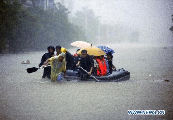 Local fire fighters transfer residents in rain in Qionghai, south China's Hainan Province, Oct. 5, 2010. On-going torrential rains poured over Hainan, causing Qionghai waterlogged while over 10,000 residents had been transferred to safe areas. [Xinhua/Meng Zhongde]