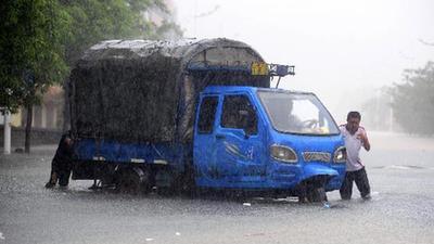 People struggle to move a switched-off vehicle on a waterlogged street in Qionghai, south China's Hainan Province, Oct. 5, 2010. [Xinhua/Meng Zhongde]