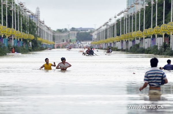 Residents pull themselves forward in a street submerged by floods in downtown Qionghai, south China's Hainan Province, Oct. 6, 2010. Continuous heavy rains poured over Hainan, causing Qionghai waterlogged while over 10,000 residents had been transferred to safe areas. [Xinhua/Guo Cheng] 