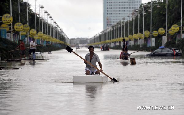 Residents paddle forward in a street submerged by floods in downtown Qionghai, south China's Hainan Province, Oct. 6, 2010. Continuous heavy rains poured over Hainan, causing Qionghai waterlogged while over 10,000 residents had been transferred to safe areas. [Xinhua/Guo Cheng]