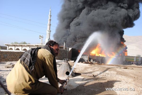 A firefighter tries to put out the fire of NATO oil tankers burnt near Pakistan's southwest city of Quetta on October 6, 2010. At least one driver was killed as some twenty NATO oil tankers were attacked by unknown gunmen early Wednesday morning near Quetta, the fourth such attack in the country since last Friday. [Xinhua/Iqbal Hussain]