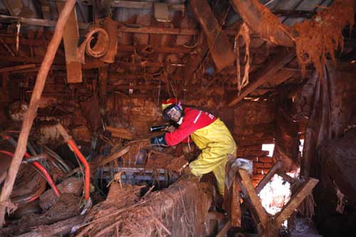 A rescue worker searches for bodies in a destroyed house in the flooded village of Kolontar, 150 km (93 miles) west of Budapest Oct 7, 2010. [China Daily/Agencies] 