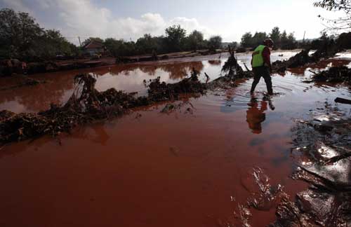 A rescue worker walks in toxic sludge in the flooded village of Kolontar, 150 km (93 miles) west of Budapest Oct 7, 2010. [China Daily/Agencies]