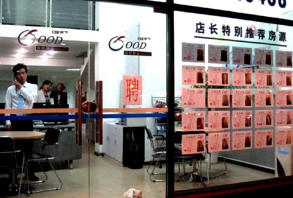 Staff work in a real estate agency in Shanghai, east China, Oct. 7, 2010. Shanghai further regulated housing market on Thursday by ordering that each family could buy no more than one set of commercial housing or apartment while the municipality was preparing the pilot project on housing tax reform at the same time. [Xinhua]