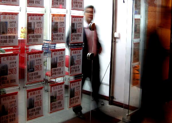 Staff walk out of a real estate agency in Shanghai, east China, Oct. 7, 2010. Shanghai further regulated housing market on Thursday by ordering that each family could buy no more than one set of commercial housing or apartment while the municipality was preparing the pilot project on housing tax reform at the same time. [Xinhua] 