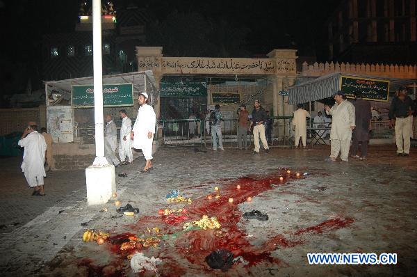 People walk near the bloodstain on the ground after blasts at a shrine in Pakistan's southern port city of Karachi, Oct. 7, 2010. At least 14 people were killed and 70 others injured in two suicide blasts that took place Thursday night at a shrine. [Toheed/Xinhua] 