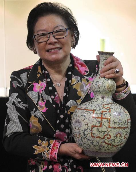 Connoisseur Alice Cheng poses with a yellow-ground famille-rose double-gourd vase that she bought at a Sotheby's auction in Hong Kong, south China, Oct. 7, 2010. The vase was sold for 252.66 million HKD at the auction, a world record for Chinese porcelain auctioned.