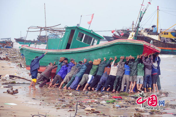 Chinese fishermen attempt to rescue a boat stranded due to floods in Qionghai, South China&apos;s Hainan province, Oct 8, 2010. The largest rainfall in 50 years forced many boats anchored in port to be pushed into the sea by flooding. Twenty boats were destroyed, local media reported. Chin&apos;s national weather forecaster, the Meteorological Administration, announced further rainstorms are expected to batter the provinces of Hainan, Yunnan and Guangdong. [Photo/CFP]