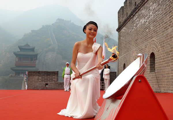 A lighter lights the flame for the 2010 Guangzhou Asian Games in Beijing on Saturday. The 2010 Asian Games Flame Lighting Ceremony is held at the Juyongguan pass of the Great Wall on Oct 9. [Xinhua] 