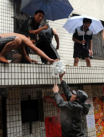 A soldier hands out food to flood-stranded residents in Wenchang city, southern Hainan province, on Friday, October 8, 2010. [Xinhua] 