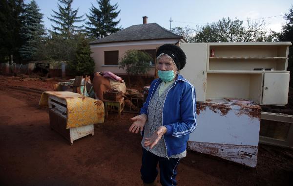 A local elderly woman stands in front of her house in the flooded town of Devecser, 150 km (93 miles) west of Hungarian capital Budapest on October 8, 2010. Wave of toxic red mud swept through the small village five days ago, killing seven and injuring scores more. [Xinhua]