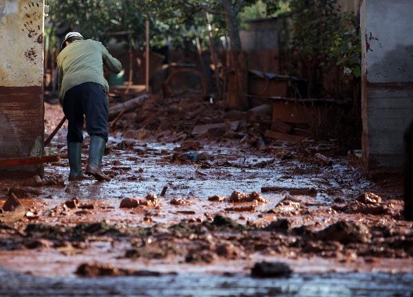 A local man cleans yard in the flooded town of Devecser, 150 km (93 miles) west of Hungarian capital Budapest on October 8, 2010. Wave of toxic red mud swept through the small village five days ago, killing seven and injuring scores more. [Xinhua]