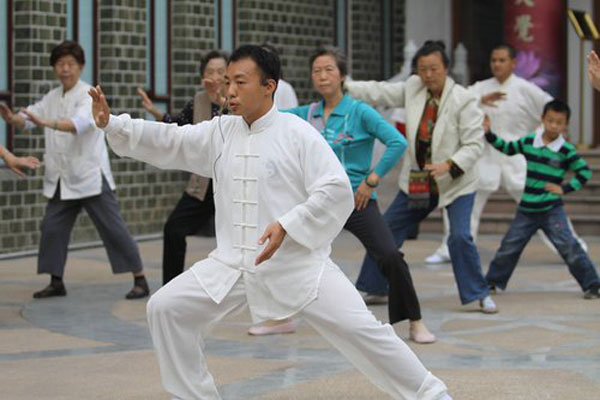Dressed in white, Chen Chao (front), a successor to the master teacher of Chen Style Tai Chi, guides people to practice the art in Wuhan, capital of Central China's Hubei province Oct 7. 