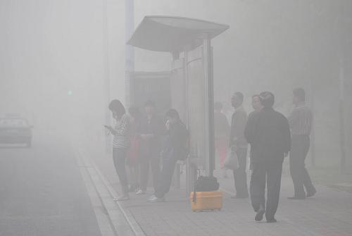 People are seen at a bus station in heavy fog in Hefei, east China&apos;s Anhui Province, Oct. 9, 2010. [Xinhua]