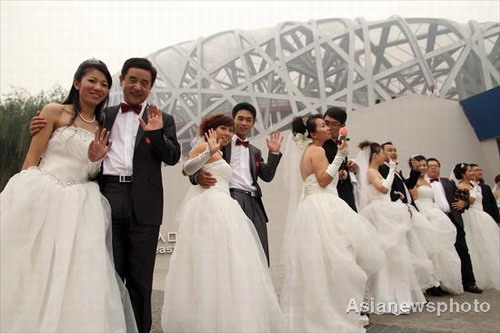 Couples pose for photos at a group wedding ceremony near the Bird&apos;s Nest, the main stadium of the Beijing 2008 Olympic Games on Sunday Oct 10, 2010. [China Daily/Asianewsphoto]