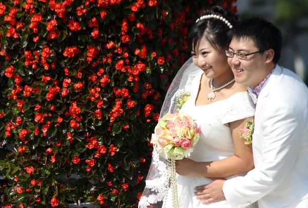 A newly-married couple pose for wedding photos at a park in Weihai, east China's Shandong Province, Oct. 10, 2010. Numerous young lovers across China got married on Oct. 10, 2010, or 10/10/10, hoping that the 'triple 10 day' will bring them good luck. In Chinese culture, many people believed that three '10's in a row means perfection. [Xinhua photo]