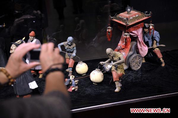 A visitor takes pictures of displayed painted sculpture works during an exhibition of Zhang Naiying, the fifth-generation successor of Clay Figure Zhang, at the National Art Museum of China in Beijing, capital of China, Oct. 10, 2010.