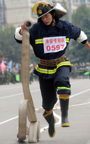 A fireman runs with a hose during a firefighting competition in Nanjing, capital of East China’s Jiangsu province, Oct 10, 2010. A total of 37 fire brigades took part in the competition which lasts for three days. [Xinhua]