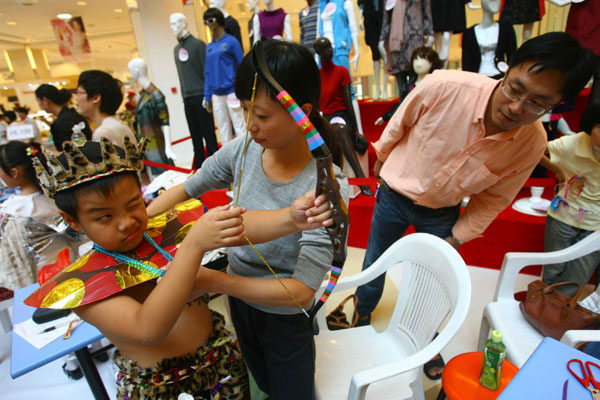 A mother helps her son dress up like a native African with an old scarf, coat hanger and other old clothes during a fashion show in Ningbo, East China&apos;s Zhejiang province on Sunday. [Xinhua]