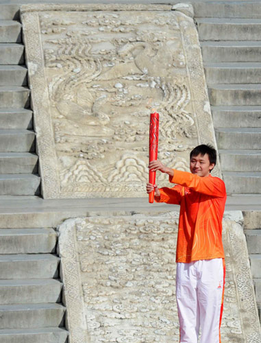 The first torchbearer Zhang Lin, China&apos;s swimming world champion, demonstrates the torch during the torch lighting ceremony and the torch relay inaugurating ceremony for 2010 Guangzhou Asian Games at the Temple of Heaven in Beijing, Oct 12, 2010. [Xinhua]