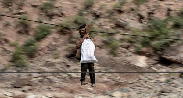 A local resident transports materials through the slide lock in Qamdo prefecture in the Tibet autonomous region on Oct 9. [Xinhua]