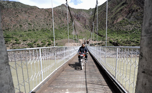 A local man rides his motorcycle on a newly built bridge in Qamdo prefecture in the Tibet autonomous region on Oct 9. [Xinhua] 