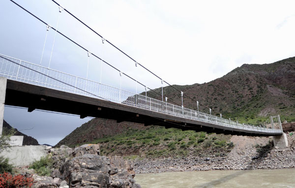 A newly built bridge will eventually replace the slide lock to help people cross the river in Qamdo prefecture in the Tibet autonomous region. [Xinhua] 