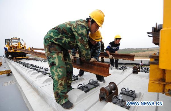 Workers operate machine to lay the railway track on Beijing-Shanghai High-Speed Railway in Cangzhou City, east China&apos;s Hebei Province, Oct. 12, 2010. The track laying operation of Beijing-Shanghai High-Speed Railway will be completed by the end of this October. [Xinhua]