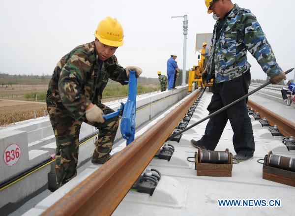 Workers adjust the track after laying the railway track on Beijing-Shanghai High-Speed Railway in Cangzhou City, east China&apos;s Hebei Province, Oct. 12, 2010. The track laying operation of Beijing-Shanghai High-Speed Railway will be completed by the end of this October. [Xinhua] 