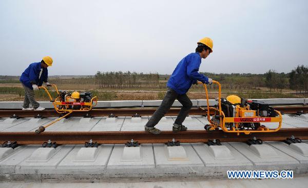 Workers adjust the track after laying the railway track on Beijing-Shanghai High-Speed Railway in Cangzhou City, east China&apos;s Hebei Province, Oct. 12, 2010. The track laying operation of Beijing-Shanghai High-Speed Railway will be completed by the end of this October. [Xinhua]